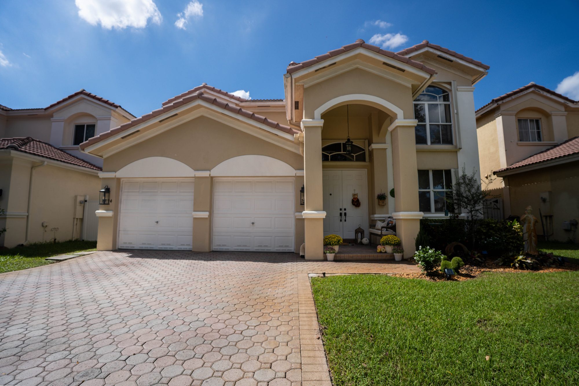 Front exterior with arched entry, tile roof and paver driveway